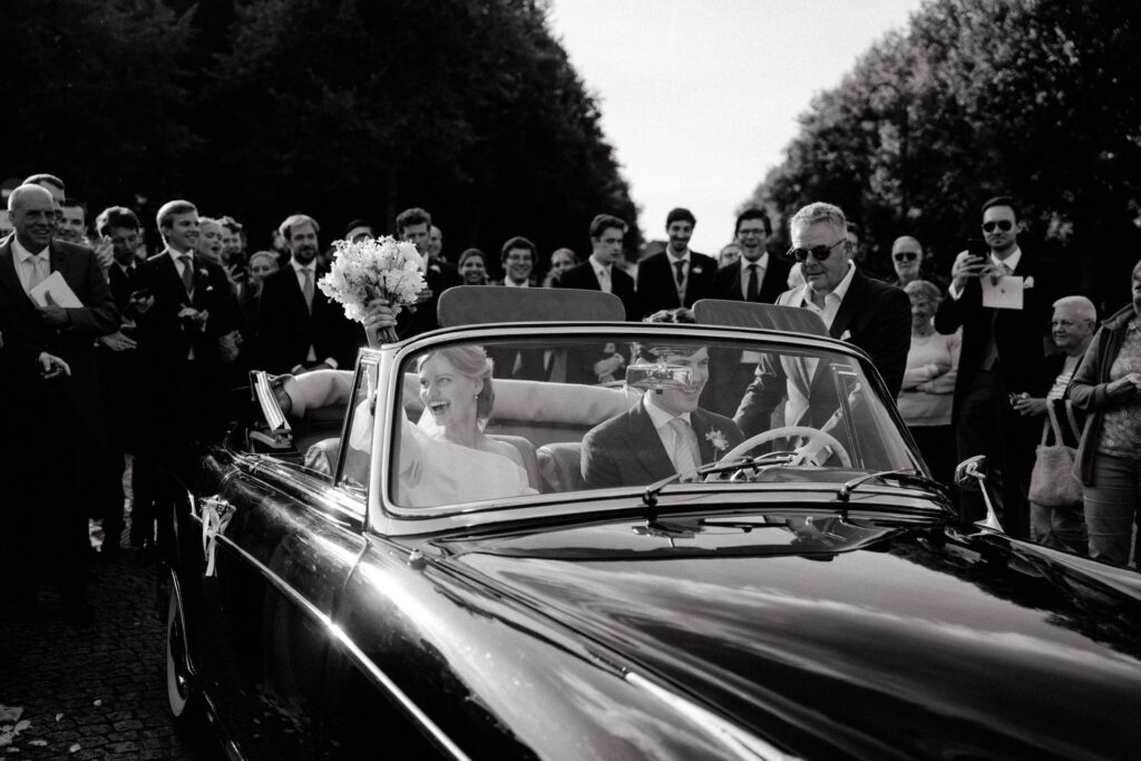 Elegant creative wedding Bride and groom leaving their ceremony in a vintage car